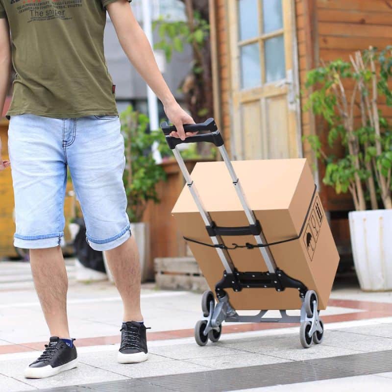 picture of a man pulling the ALL TERRAIN MULTIFUNCTIONAL STAIRS CLIMBING CART. He is carrying some boxes on it