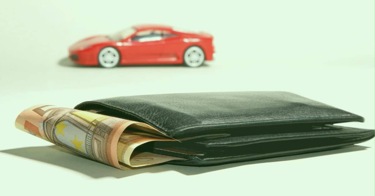 A wallet with some cash hanging out of it with a fancy car in the backgrounds. It  depicts the wants of people who are prone to borrowing. 